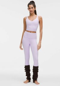 Light purple cropped tank top and matching leggings, paired with dark brown textured leg warmers. Smooth fabric, fitted silhouette.