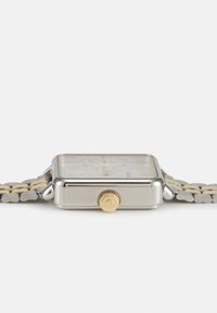 Montre carrée en argent avec accent doré sur la couronne, cadran clair, marqueurs dorés et un bracelet bicolore semi-métallique.