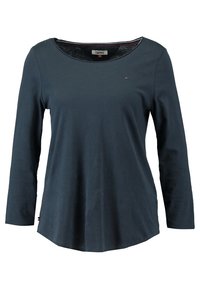 Tmavě modrá košile s dlouhým rukávem a kulatým výstřihem, vyrobená z lehkého materiálu, s decentním logem na hrudi a zakřiveným lemem.