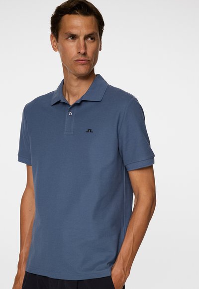 Heren polo shirt met korte mouwen in het blauw, gemaakt van gestoffeerde stof. Heeft een klassieke kraag, een placket met twee knopen en een klein zwart logo op de borst.
