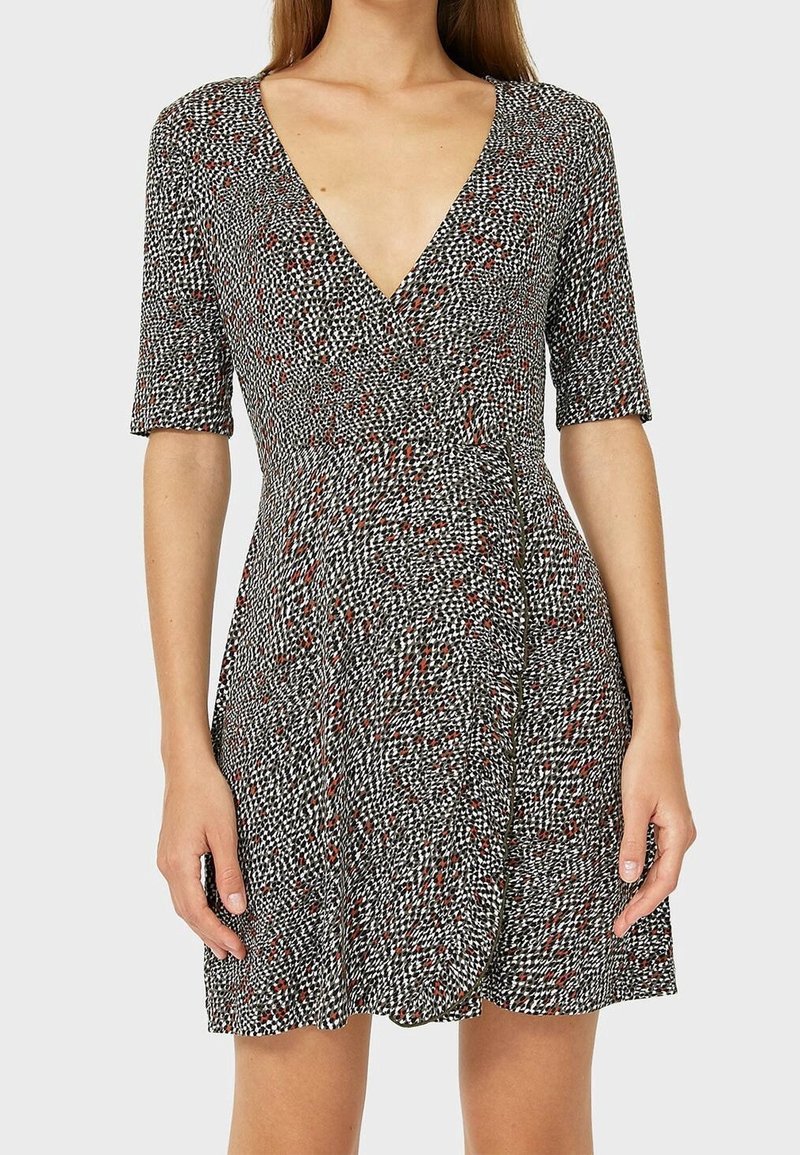 Vestido de patrón blanco y negro con escote en V, mangas cortas y falda acampanada, que presenta acentos rojos y un corsé ajustado.