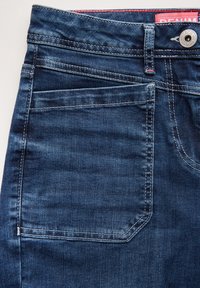 Mörkblå denimjeans med en klassisk femficksdesign, synlig sömnad och metalldetalj för knäppning i midjan.