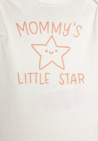 Body en coton blanc avec un texte orange qui dit "LA PETITE ÉTOILE DE MAMAN" accompagné d'une illustration d'étoile souriante. Texture douce et lisse.