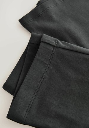 Leggings neri in cotone con una texture liscia, piegati con cuciture ordinate lungo i bordi, presentano un design semplice e funzionale.