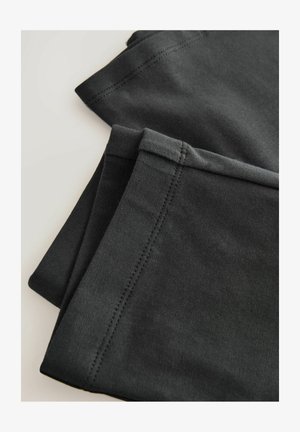 Zwarte katoenen leggings met een gladde textuur, netjes gevouwen met een nette stitching langs de randen, hebben een eenvoudig, functioneel design.