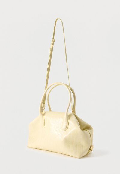 Μαλακή κίτρινη τσάντα από δερμα με υφή, με δύο λαβές και ένα μακρύ ρυθμιζόμενο λουρί ώμου, που παρουσιάζεται πάνω σε απλό ανοιχτόχρωμο φόντο.