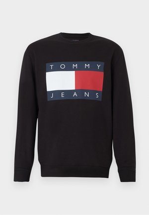 Svart långärmad crewneck sweatshirt med Tommy Jeans-logotyp som har en marinblå, vit och röd rektangulär flagga på bröstet.