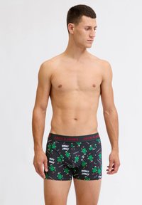 Caleçons boxers noirs avec un motif de monstre en cartoon vert et une ceinture rouge "JACK & JONES". Tissu doux avec un ajustement serré.
