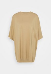 T-shirt beige oversize à manches courtes avec encolure ronde, coupe ample et design uni sur fond blanc.