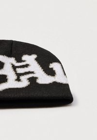 Căciulă neagră tricotată cu model grafic alb, având coroană rotunjită și margine pliată, realizată din material moale și texturat.