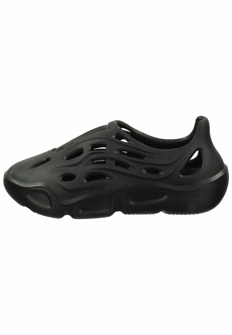 Chaussure noire sans lacets avec plusieurs trous de ventilation en forme d'ondes et de cercles, semelle épaisse et bout arrondi.