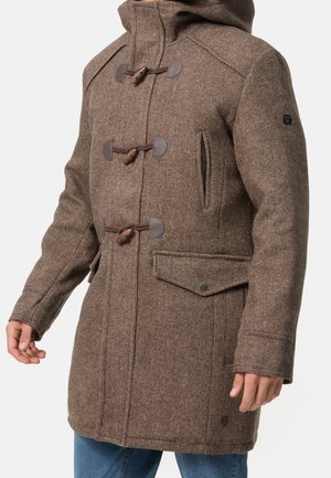 Manteau à capuche en laine marron avec boutons à bascule et poches avant porté par une personne en jean bleu sur fond blanc.