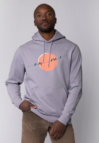 Lichtgrijze hoodie met een voorkant kangaroo zak, voorzien van een grote oranje cirkelafbeelding met silhouetten van vogels op een draad.