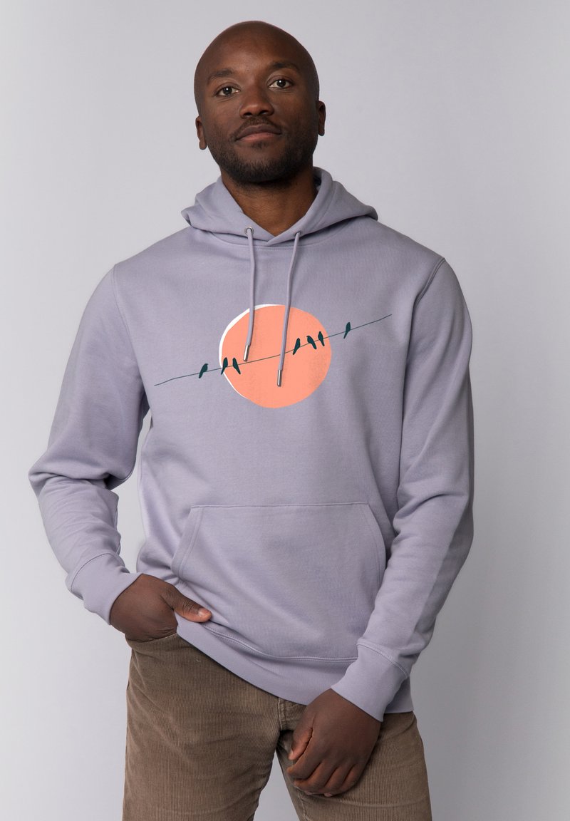 Lichtgrijze hoodie met een voorkant kangaroo zak, voorzien van een grote oranje cirkelafbeelding met silhouetten van vogels op een draad.
