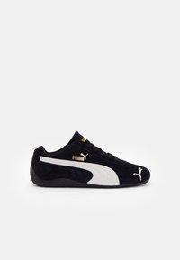 Baskets en daim Puma noires avec bande blanche, logo doré Puma sur le côté et la languette, et logo chat Puma blanc sur l’avant, vues de profil.