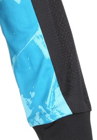 Pantalons de sport avec un design bleu et noir, texture lisse sur la partie bleue et un motif hexagonal sur le panneau latéral noir.