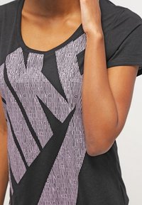 Svart t-shirt med en stor, texturerad rosa grafisk design. Korta ärmar och vid halsringning, tillverkad av mjukt bomullsmaterial.