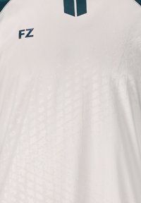 Valkoinen urheilupaita, jossa on teksturoitu kuosi, tummanvihreät korostukset harteilla ja "FZ"-logo vasemmalla puolella.