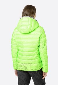 Chaqueta acolchada verde lima con capucha, que presenta un diseño acolchado, un acento blanco en el cuello y detalles en texto en la parte posterior.