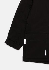 Giacca nera con un tessuto testurizzato, dotata di una chiusura con zip, polsini elasticizzati, una grande tasca e dettagli del logo riflettente sul lato.