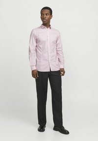 Hellrosa Langarmhemd mit einem Button-down-Kragen, schlanker Schnitt, getragen mit schwarzen Hosen und schwarzen Schuhen; glatte Textur, subtiler Glanz.