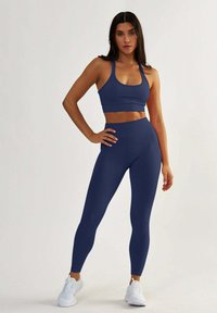 Granatowy sportowy top krótki i legginsy z gładkiego, elastycznego materiału. Legginsy mają wysoki stan i dopasowany krój.