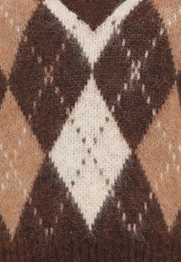 Strikket sweater med et stort argyle-mønster i brun, beige og creme, med en blød tekstur og synlige fibre i stoffet.