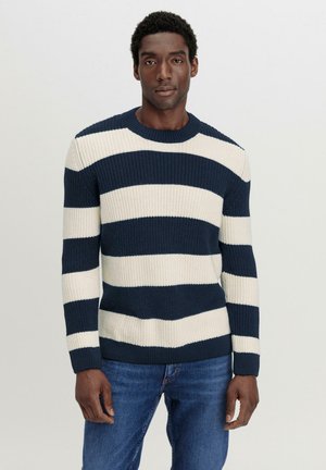 Strickpullover mit horizontalen Streifen in Marineblau und Creme, Rundhalsausschnitt, gerippte Bündchen und einem strukturierten Stoff. Kombiniert mit blauen Jeans.