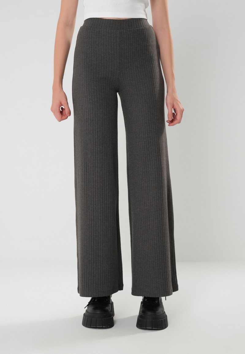 Breda byxor i ribbat tyg i mörkgrått med hög midja och texturerade detaljer, i kombination med svarta platåstövlar.