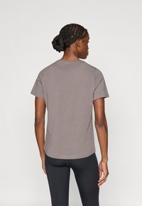 Gray cotton t-shirt with short sleeves and a round neck, featuring a straight hem and minimal stitching detail at the seams.