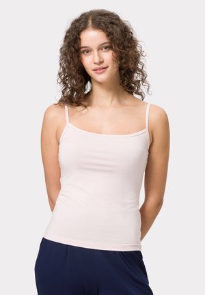 Lichtroze tanktop met dunne bandjes, gemaakt van gladde stof. Vierkante halslijn en een strakke pasvorm, gecombineerd met donkere, losse broek.