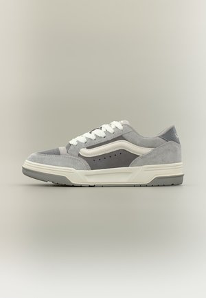 Γκρι και λευκό χαμηλό sneaker με λευκά κορδόνια, λεπτομέρεια πλευρικής ρίγας, περφοραρισμένα σημεία και παχιά λευκή σόλα, εμφανίζεται σε προφίλ σε ουδέτερο φόντο.
