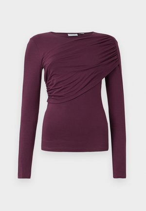 Dlhý rukáv top v hlbokej burgunďskej farbe, vyrobený z mäkkej tkaniny. Obsahuje nazhromaždené detaily na prednej strane a okrúhly výstrih.