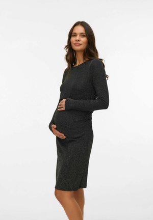Robe de maternité, manches longues, design ajusté en noir avec un subtil scintillement argenté. Texture douce, longueur genoux. Détail froncé à l'avant.