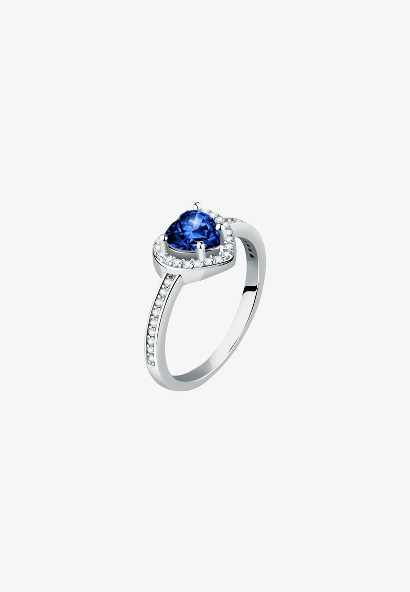Anello a forma di cuore con un grande gemma blu, montato su argento lucido, con una fascia decorata da piccole pietre trasparenti lungo un lato.