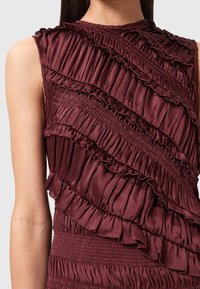 Abito borgogna con strati arricciati e vita a corsetto. Presenta un design a spalla unica e un materiale testurizzato simile alla seta.