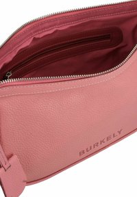 Pocchetto in pelle rosa con finitura testurizzata, chiusura a zip e fodera interna bordeaux con tasca con zip. Nome del marchio "BURKELY" impresso.