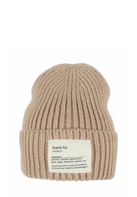Beige knit beanie with ribbed texture and a folded cuff. Features a white tag with text defining "thankful" and its synonyms.
