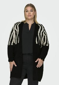 Zwart en crèmekleurige gestreepte cardigan met lange mouwen, een relaxed fit, ribgebreide manchetten, twee voorkruiszakken en een open voorkant.
