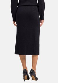 Zwarte geribbelde kokerrok met een middellange uitstraling, aangevuld met zwart, hooggehakt schoenen met krokodillenpatroon. De textuur lijkt glad en aansluitend.