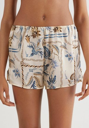 Brocade sovshorts i krämfärg med blå och bruna blommönster, elastisk midja och slät satinkänsla. Skräddarsydd passform med sidoklyftor.