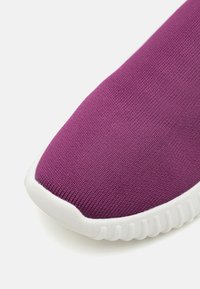 Purple knitted sneaker featuring a textured upper, a rounded toe, and a white rubber sole with ridged detailing.