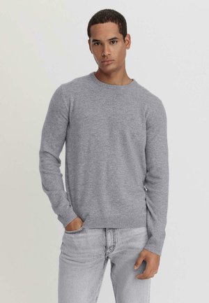 Pullover grigio con collo a giro realizzato in un morbido tessuto testurizzato, con polsini e orlo a coste, abbinato a jeans grigio chiaro per un look completo.