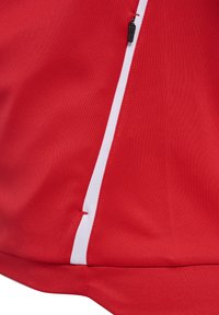 Rode stof met witte verticale streep en zwarte rits, een close-up van een jas of sportkleding.