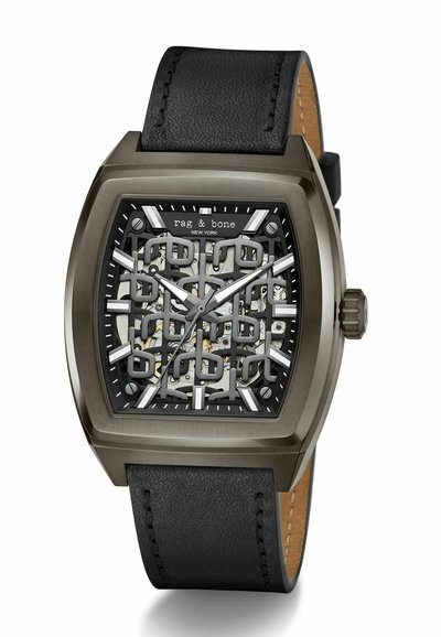 Quadratische Uhr mit schwarzem Lederarmband, grauem Metallgehäuse und transparentem Ziffernblatt, das komplexe Mechanik und graue, schwarze Akzente offenbart.