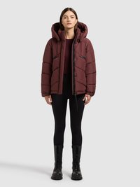 Kirsipunane padi-jope kapuutsiga, horisontaalse tikkimismustriga, tõmblukk ja klõpskinnitusega, kombineeritud mustade retuuside ja pits-up mustade saapadega.