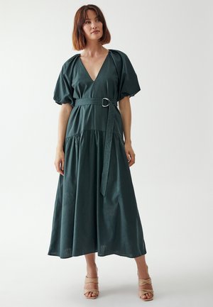 Green, floor-length dress with short puff sleeves, a deep V-neck, cinched waist with a silver buckle, and gathered skirt detail.