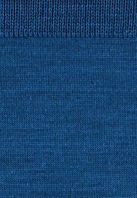 Close-up van blauw gebreide stof met zichtbare stekenstructuur en geribbelde randdetails.