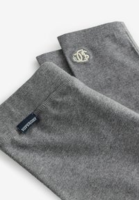 Prehnuté šedé textilné rukávy s nálepkou Superdry a malou vyšitou bielou logom na jednom rukáve.