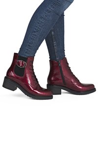 Bottines bordeaux à fini brillant, avec lacets, fermeture éclair latérale, panneau élastique et un accent métallique circulaire. Talon noir épais.